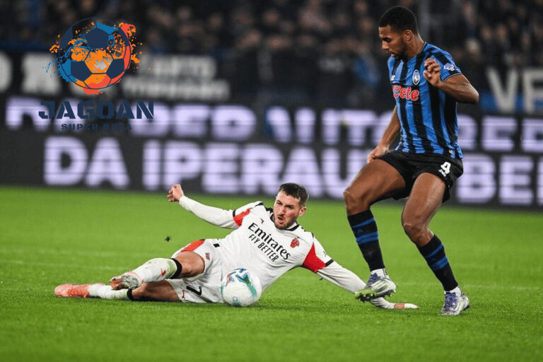 Pemain bertahan melakukan tekel untuk merebut bola dalam pertandingan Liga Italia, dengan logo Jagoan Super Bola di latar gambar.