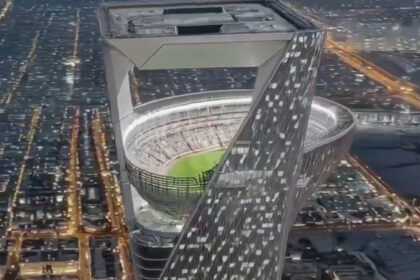 Gedung pencakar langit modern dengan stadion terbuka di puncaknya pada malam hari