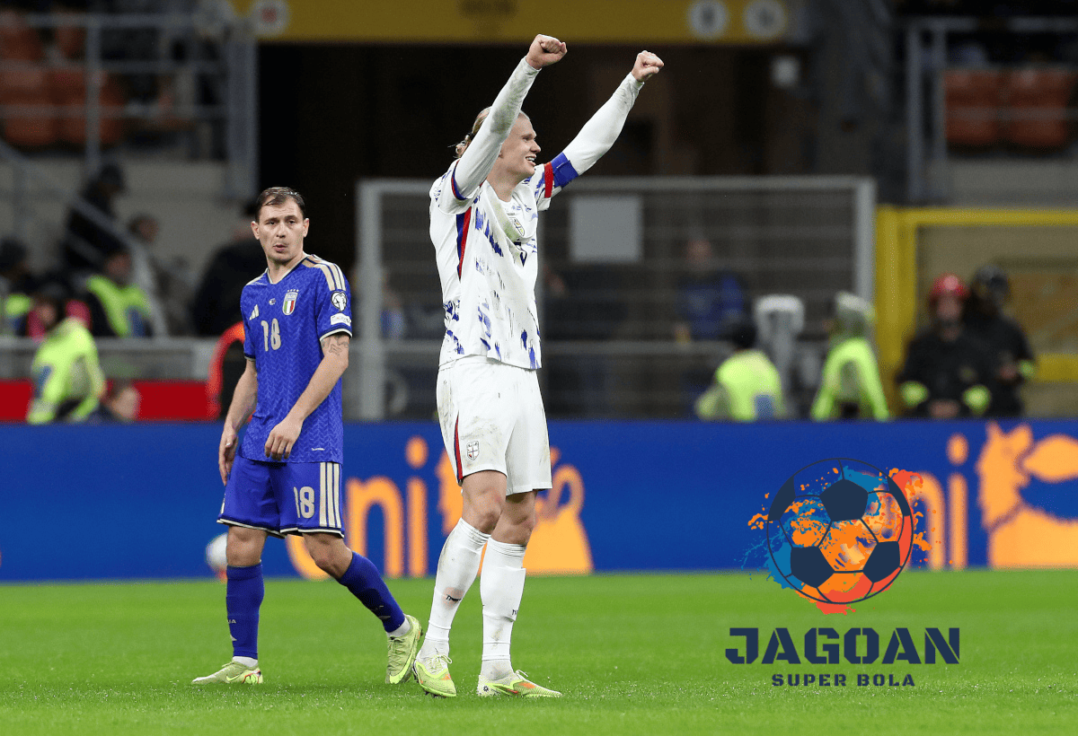 Pemain tim nasional melakukan selebrasi di lapangan setelah pertandingan, sementara pemain lawan berjalan di belakangnya dalam laga sepak bola internasional.