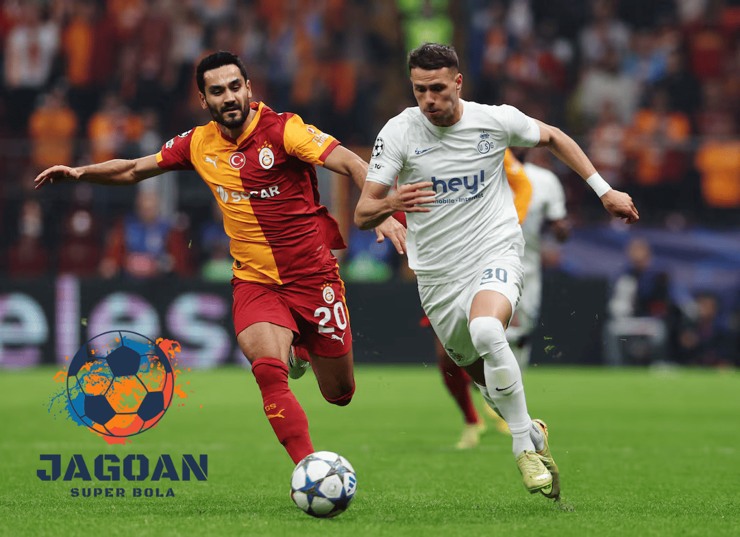 Dua pemain dari Galatasaray dan tim lawan berebut bola pada pertandingan kompetisi Eropa di stadion.