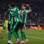 Pemain sepak bola Real Betis merayakan gol bersama di tengah pertandingan dengan logo Jagoan Super Bola pada sudut gambar.