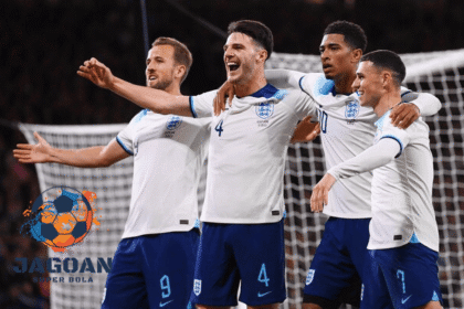 Pemain timnas Inggris merayakan gol bersama di lapangan sepak bola saat laga internasional, mengenakan jersey putih biru dengan ekspresi gembira.