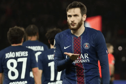 Seorang pemain PSG melakukan selebrasi di lapangan dengan rekan setim di latar belakang.