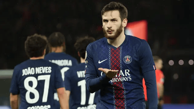 Seorang pemain PSG melakukan selebrasi di lapangan dengan rekan setim di latar belakang.