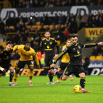 Pemain sepak bola melakukan tendangan penalti saat pertandingan melawan tim berseragam kuning di stadion.