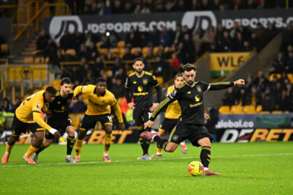 Pemain sepak bola melakukan tendangan penalti saat pertandingan melawan tim berseragam kuning di stadion.