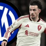 Curtis Jones pemain Liverpool FC mengenakan jersey putih bergaris merah dengan sponsor Standard Chartered dan logo LFC dalam posisi siap bertanding di lapangan sepak bola