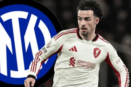 Curtis Jones pemain Liverpool FC mengenakan jersey putih bergaris merah dengan sponsor Standard Chartered dan logo LFC dalam posisi siap bertanding di lapangan sepak bola