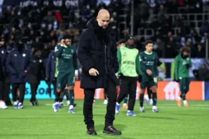Pep Guardiola berjalan di lapangan usai pertandingan Liga Champions bersama pemain Manchester City