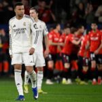 Pemain Real Madrid tertunduk dengan seragam putih Emirates Fly Better sementara para pemain Osasuna berbaju merah merayakan gol pada laga La Liga